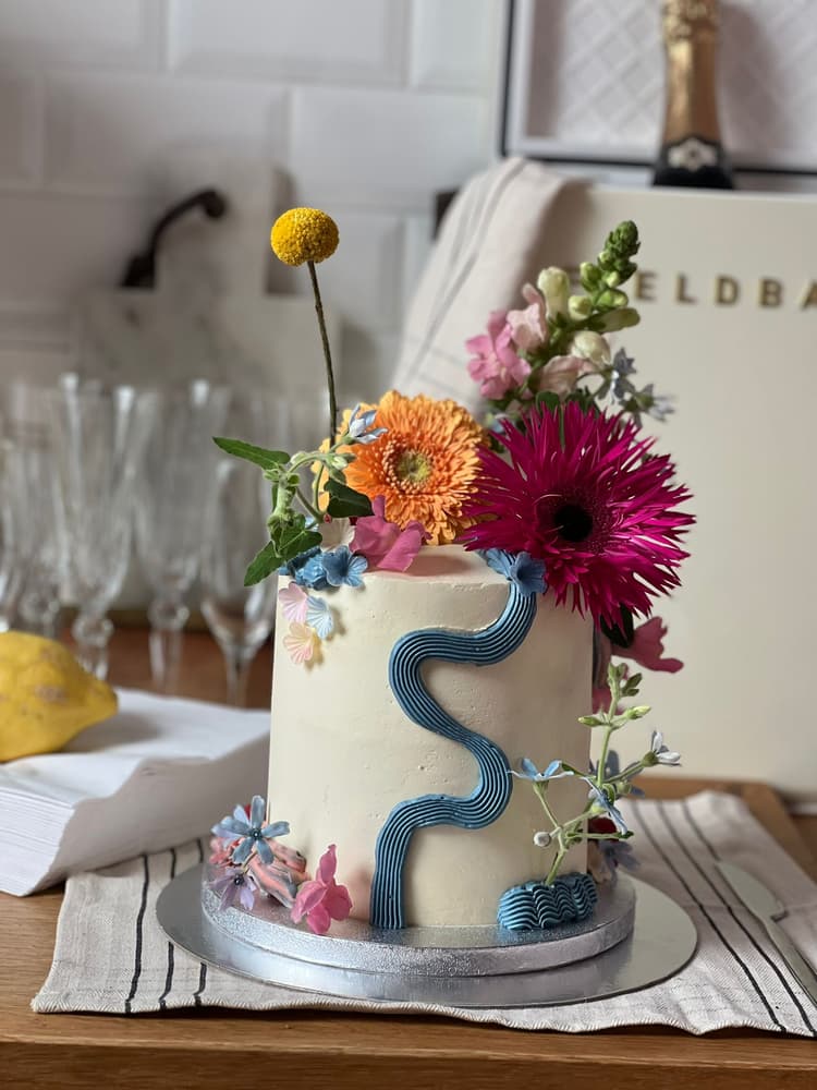 EIne hübsche Torte mit bunten Blüten oben drauf. 